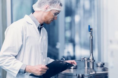 Bilim Laboratuarı 'nda çalışan bilim adamı tıbbi fabrika çalışanı. İlaç fabrikası teknisyeni Bakım Bakım Bakım Ürünleri Kalitesi Sterilize Odasında Not Alma Listesi.