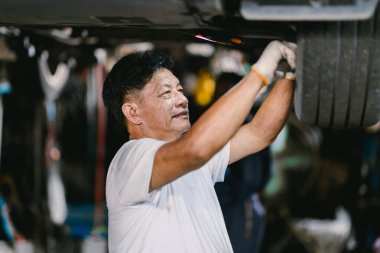 Araba Servisi 'nde Tamir Aracı' nda çalışan mutlu Asyalı tamirci. Süspansiyon sistemini tamir eden işçiler.