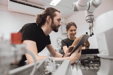 Endüstriyel Robotik Programı üniversite öğrencileri mühendislik laboratuvarı sınıfında robot robot kolu simülasyonu modeli ile eğitim mekanik birleşimi öğreniyor..