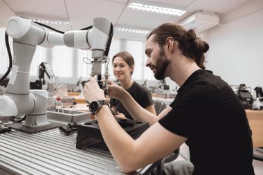 Endüstriyel Robotik Programı üniversite öğrencileri mühendislik laboratuvarı sınıfında robot robot kolu simülasyonu modeli ile eğitim mekanik birleşimi öğreniyor..