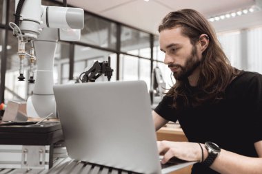 Mühendis adam üniversite öğrencisi kontrol işletimini öğrendi ve robot kolu robotik mühendisleri laboratuvar sınıfında politeknik eğitimde dizüstü bilgisayarla programladı..