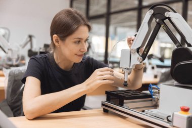 Engineer women learning education in Industrial Robotics program with robot arm simulation model in university engineering lab classroom. clipart