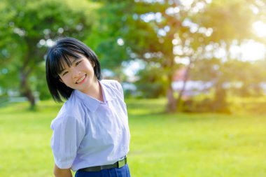 Portre mutlu gülümseme Asyalı liseli kız yeşil parkın dışında fotokopi alanı olan üniformalı kız.