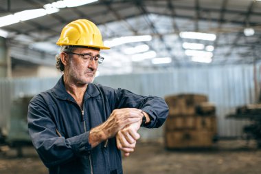 Mühendis, kol saatinin çalışma saatine bakıyor. Sanayi fabrikası geç saate kadar çalışma konsepti.