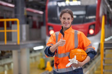 Portre mühendisi kadınlar yeraltı lokomotifi bakım elemanı tren istasyonunda gülümseyen parmaklar arasında duruyor..