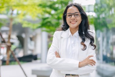 portrait Indian business women female standing happy smile. businesswomen arm folded happy in green city outdoors. clipart