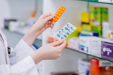 Eczacı doktor elinde karışık ilaç paketi ile eczanedeki ilaç seçimini veya tercihini karşılaştırıyor.