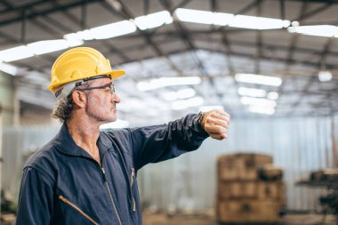 Kıdemli işçi kol saatindeki saate bakıyor. Öğle yemeği frenini bekliyor..