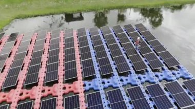 Mühendislik Servisi Yüzen Güneş Paneli hava görüntüsü 4K video kaydı. Profesyonel işçi, göl gölündeki güneş enerjisi çiftliğinin bakımını üstlendi..