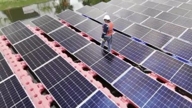 Mühendislik Servisi Yüzen Güneş Paneli hava görüntüsü 4K video kaydı. Profesyonel işçi, göl gölündeki güneş enerjisi çiftliğinin bakımını üstlendi..