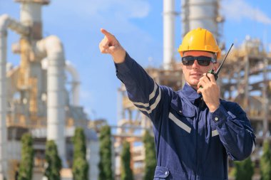 Petrol endüstrisi mühendisi dışarıda çalışıyor. Rafineri tesisi petrol ve gaz servis kontrol kontrol büyük kompleks gaz boru binası önünde radyo ile bakım.