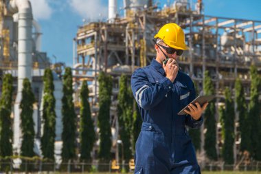 Petrol endüstrisi mühendisi dışarıda çalışıyor. Rafineri yağı ve gaz servisi ustabaşı tablet ve telsizle karmaşık gaz boru binasının bakımını üstleniyor..