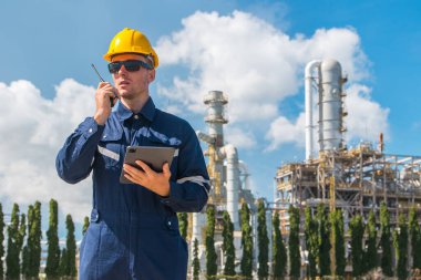 Petrol endüstrisi mühendisi dışarıda çalışıyor. Rafineri yağı ve gaz servisi ustabaşı tablet ve telsizle karmaşık gaz boru binasının bakımını üstleniyor..