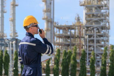 Rafineri petrol işçisi görev başında, telsiz kontrol operasyonu. Petrol ve gaz endüstrisi mühendisi petrokimya fabrikasında çalışıyor..