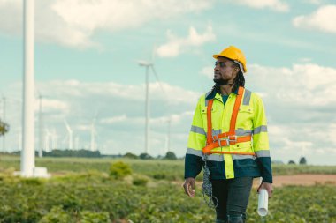 African black engineer technician male worker working service maintenance wind turbine at Wind Turbines electricity generator farm field outdoors. clipart