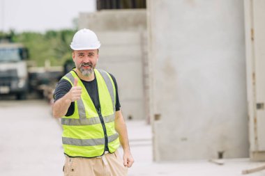 İnşaat işçisi. Beyaz erkek. İnşaat alanında mutlu bir şekilde gülümsüyor.,