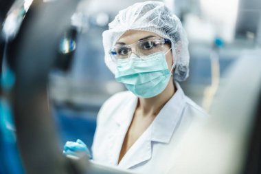 Hijyen kadın çalışanı bilim laboratuarında çalışıyor. İlaç üretim makinesi müfettişleri..