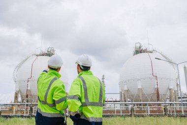 Rafineri petrol ve gaz tankında çalışan endüstri mühendisleri, mühendis arkadaşlarıyla petrol depolama sahasında işbirliği yapıyor..
