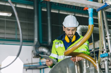 Endüstriyel fabrika işçisi, gıda ve içecek fabrikasında çalışan mühendis personeli, tesisteki sıvı boru tedariğinin kalitesini kontrol ediyor..