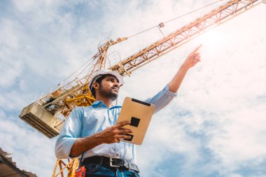 Hintli inşaat mühendisi inşaat alanı kontrol operasyonu. Foreman, vinçle tableti tutuyor..