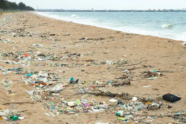 Çöpler sahilde yıkandı, kirli deniz çöpleri, plastik bardaklar ve plajda plastik torbalar. Çevresel okyanus ve kıyı sorunu.