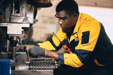 Afrikalı zenci işçi ağır metal endüstrisinde çalışıyor çelik makinelerini yumrukluyor.