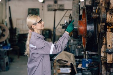 Kafkasyalı kadınlar ağır sanayi fabrikasındaki eski makineleri teftiş ediyorlar.