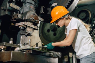 Ağır endüstri fabrikasında çalışan kadın teknisyen servis bakım makinesini tamir ediyor.