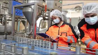 Mühendis ekibi, gıda fabrikası üretim hattında güvenlik için servis bakım makinesini kontrol ediyor.