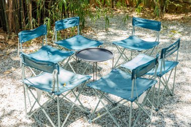 piknik masası, bir grup sandalyeyle kurulmuş açık hava orman parkı. Kimse yok.