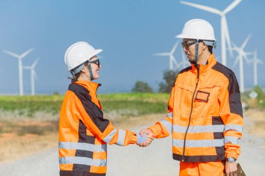 Dışarıdaki rüzgar türbini enerji çiftliğinde çalışan mühendis el sıkışma ekibi desteği. Profesyonel modern işçiler takım çalışması kavramı.