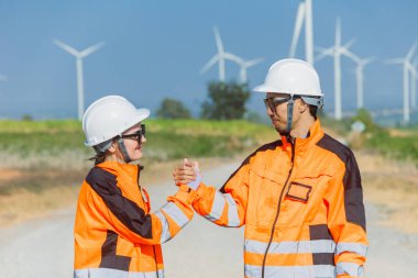 Dışarıdaki rüzgar türbini enerji çiftliğinde çalışan mühendis el sıkışma ekibi desteği. Profesyonel modern işçiler takım çalışması kavramı.