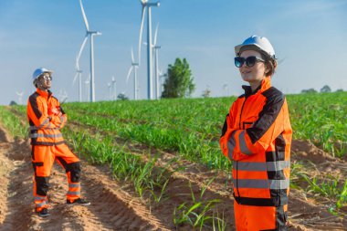 Çevre dostu konsept için tarımsal rüzgar türbini çiftliğinde kendinden emin duran mühendis genç işçi takımı çevre dostu konsept için yeşil enerji üretiyor..