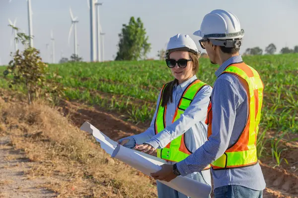 Profesyonel mühendis ekip çalışması alanında rüzgar türbini tarım projesi mavi baskıyı birlikte planlıyorlar. Rüzgar enerjisi jeneratörü çiftlik inşaatı.