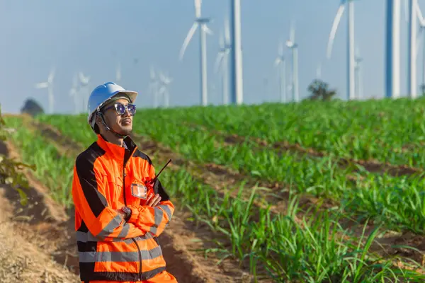 Asyalı mühendis erkek işçinin portresi tarımsal rüzgar türbini çiftliğinde çevre dostu kavram için yeşil enerji ile kesişiyor..