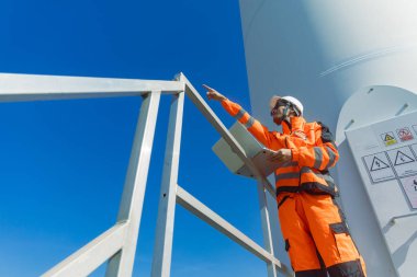 Profesyonel Asyalı mühendis teknisyen erkek işçi servis onarım rüzgar türbini temiz elektrik santralini kontrol ediyor. Rüzgar enerjisi jeneratörü çiftliği..