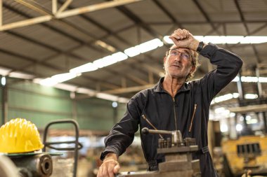 Kıdemli işçi ağır iş fabrikasında çalışmaktan yorgun düşmüş baş ağrısı çekiyor..