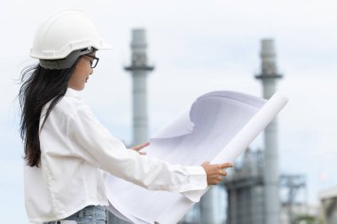 Rafinerinin elektrik santrali zemin planına karşı duran profesyonel zeki genç mühendis kadınlar. büyük endüstri inşaat projesi yönetim kavramı.