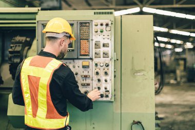 Profesyonel teknisyen erkek, fabrikada ağır sanayi makinası CNC 'yi çalıştırıyor. İşçi makine düğmesine basıyor..