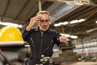 Kıdemli işçi ağır iş fabrikasında çalışmaktan yorgun düşmüş baş ağrısı çekiyor..