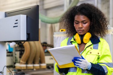 Afrikalı siyahi kadın işçiler ahşap kesici makine mobilya fabrikası ve güvenlik kıyafeti ile çalışıyorlar.