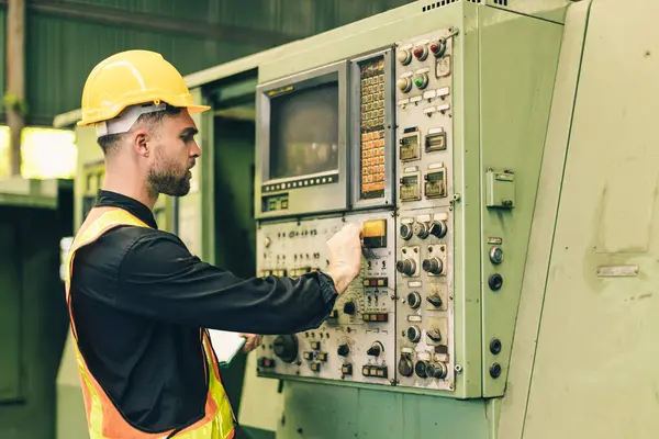 Profesyonel teknisyen erkek, fabrikada ağır sanayi makinası CNC 'yi çalıştırıyor. İşçi makine düğmesine basıyor..