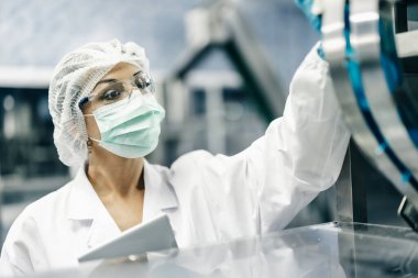 Endüstri müfettişi ekibi çalışıyor, QC personeli içki fabrikasında güvenlik ve hijyen için makine operasyonlarını kontrol ediyor.