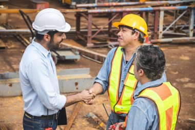 İnşaat alanında çalışan müteahhitlerle el sıkışma anlaşması. Mühendis projesi iş bağlantısı insanlar kavramı.