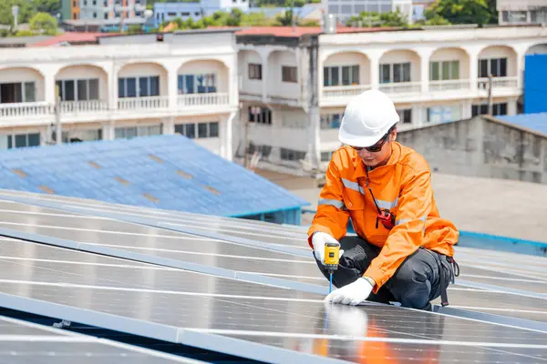 Sanayi binasının çatısına güneş panelleri kuran işçiler, yeşil eko enerji arzı için büyük ölçekli güneş enerjisi sistemi