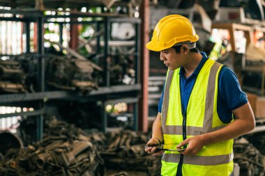Hurdalıkta çalışan teknisyen erkek işçi depodaki depolama alanındaki müşteriden ikinci el araç motoru siparişi alıyor.