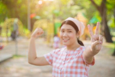 Şirin, genç, Asyalı, sağlıklı, tombul bir kadın açık hava sporları eğlence parkında gülümsüyor.