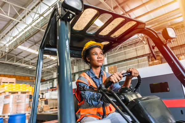 Depo çalışanı forklift sürücüsü mutlu bir gülümseme ile çalışanların keyfini çıkar. Afrikalı siyahi kadınlar fabrika kargo işçisi