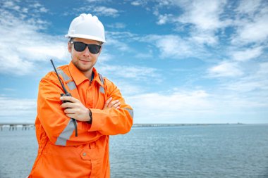 Profesyonel, zeki, kendine güvenen, beyaz, erkek, okyanus arka planında çapraz duran.