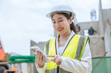 Akıllı telefon bağlantısı kullanan, sohbet mesajı yazan iş bağlantılarını okuyan mutlu inşaat mühendisi kadınlar